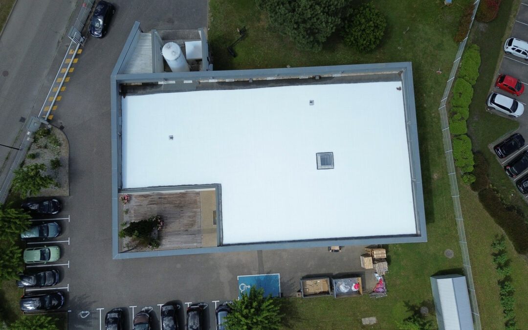 Vue aérienne d’une toiture-terrasse blanche sur un bâtiment professionnel.